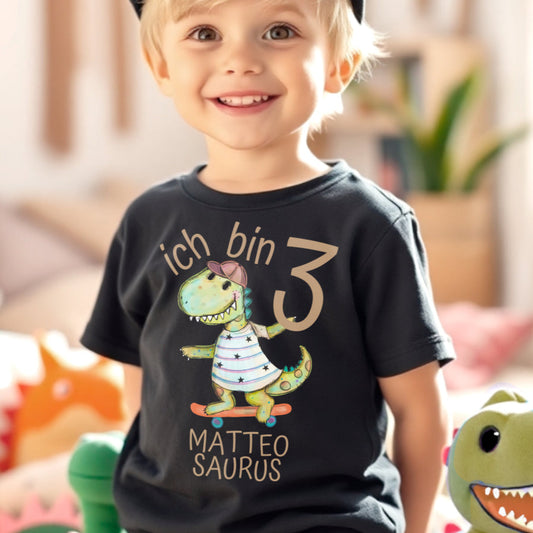 Junge trägt ein personalisiertes Shirt zum 3. Geburtstag mit seinem Namen 'Matteo', seinem Alter und einem Dino-Motiv.