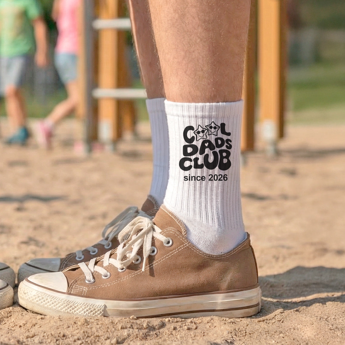 Weiße Tennissocken mit dem schwarzen Aufdruck Cool Dads Club und personalisierten Jahreszahlen, getragen von einem Mann in lässigen Sneakern.