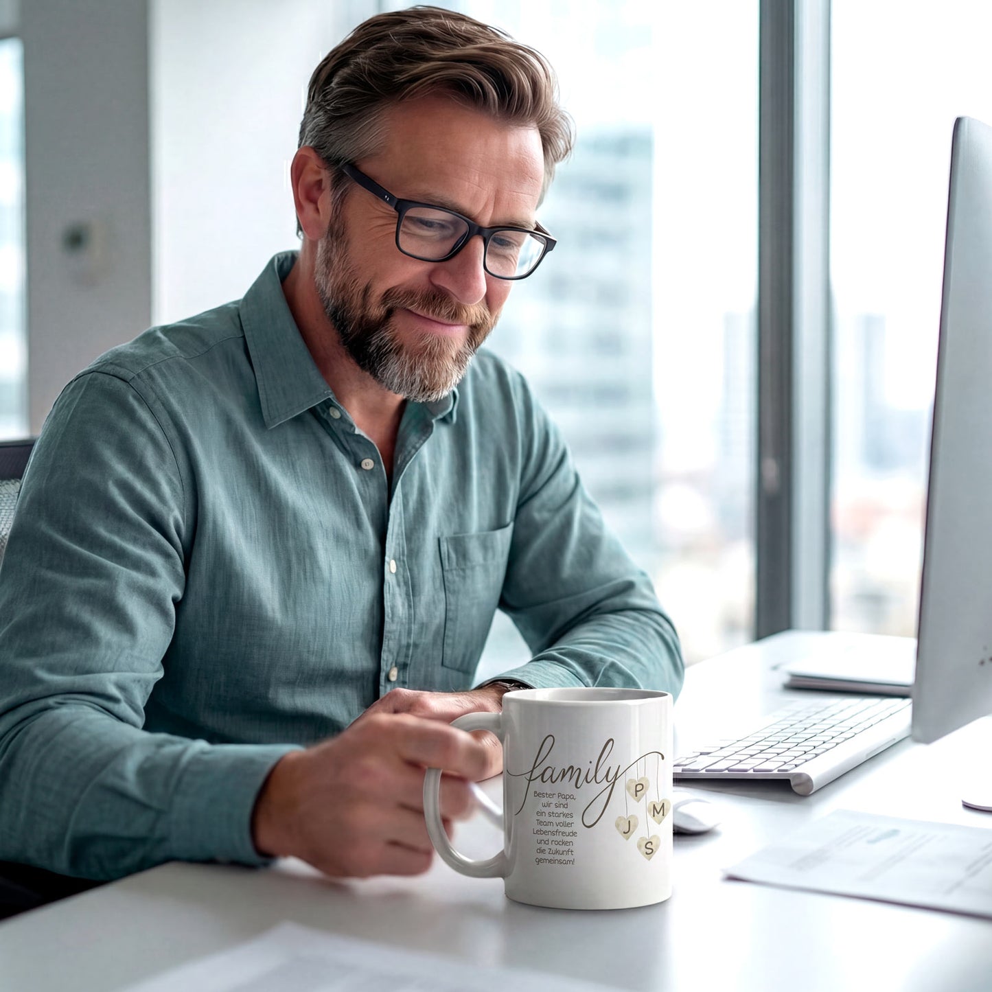 Ein Vater sitzt im Büro und schaut lächelnd auf seine personalisierte Kaffeetasse mit Familien-Initialen. Modernes Lifestyle-Design im modernen Stil.