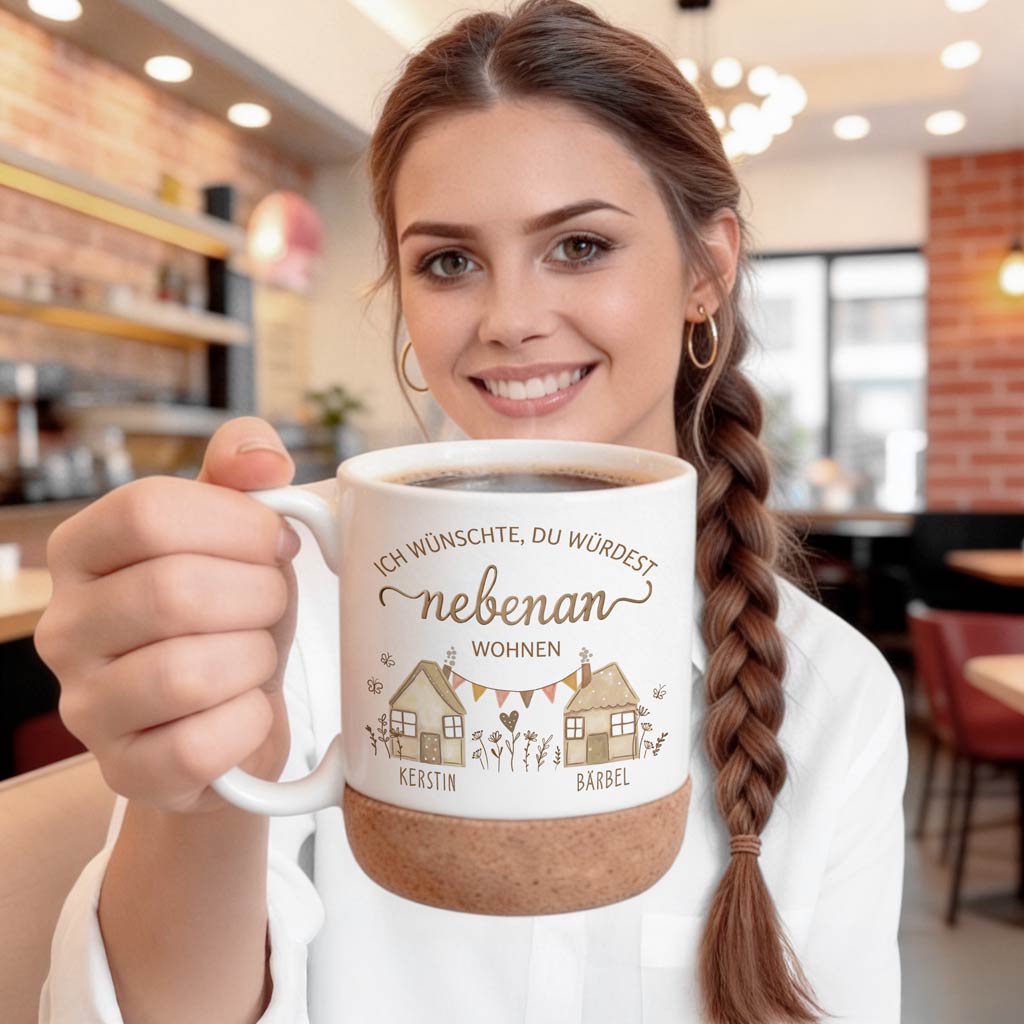 Eine Freundin hält eine personalisierte Tasse mit Spruch Ich wünschte du würdest nebenan wohnen und zwei Häusern stolz in der Hand.