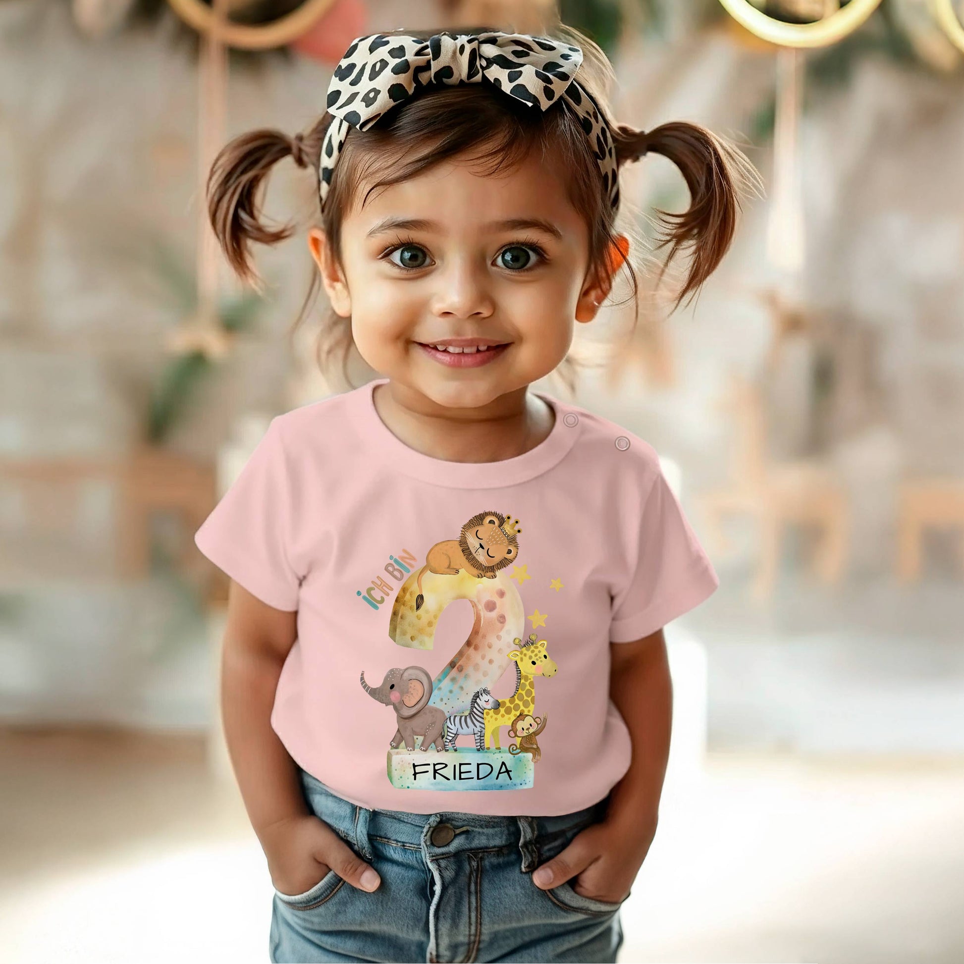 Mädchen trägt ein rosa Geburtstagsshirt mit einer Dschungeltier-Grafik und der Zahl 2 im Leo-Print.
